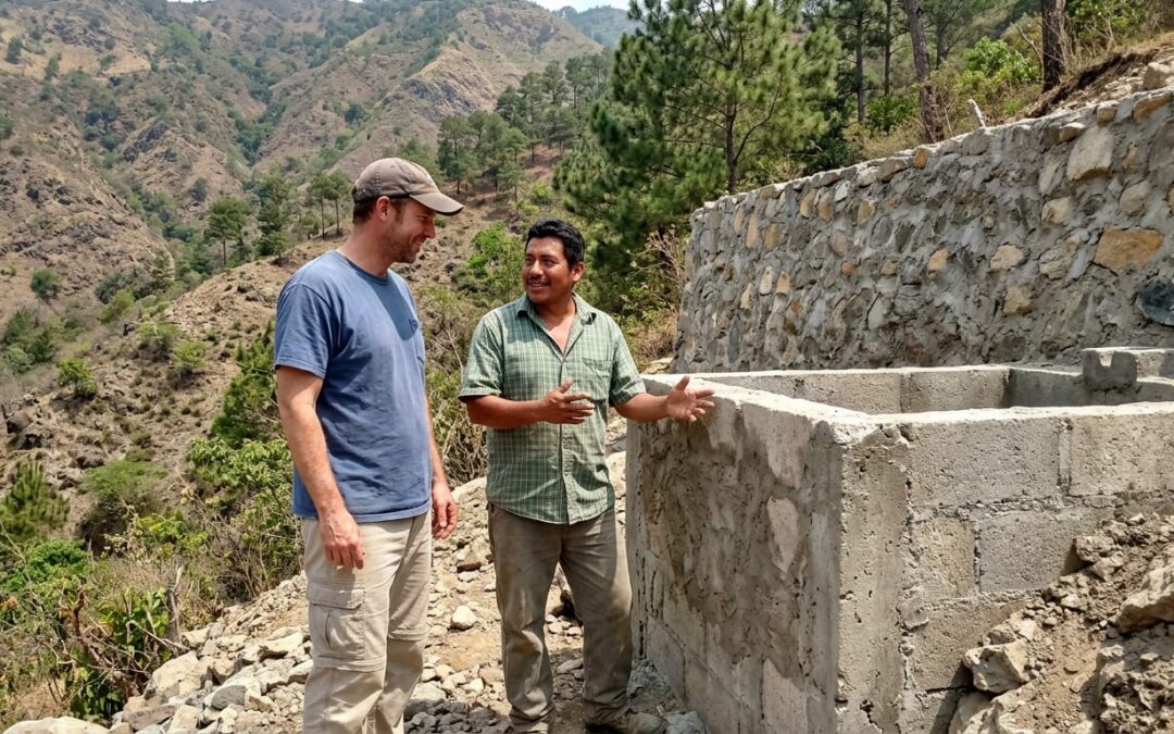 Donor and local partner examining a water cistern on a rocky hillside in Honduras during a nonprofit site visit.